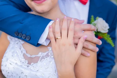 A menyasszony és a vőlegény gyűrűs keze közeli esküvői portrén